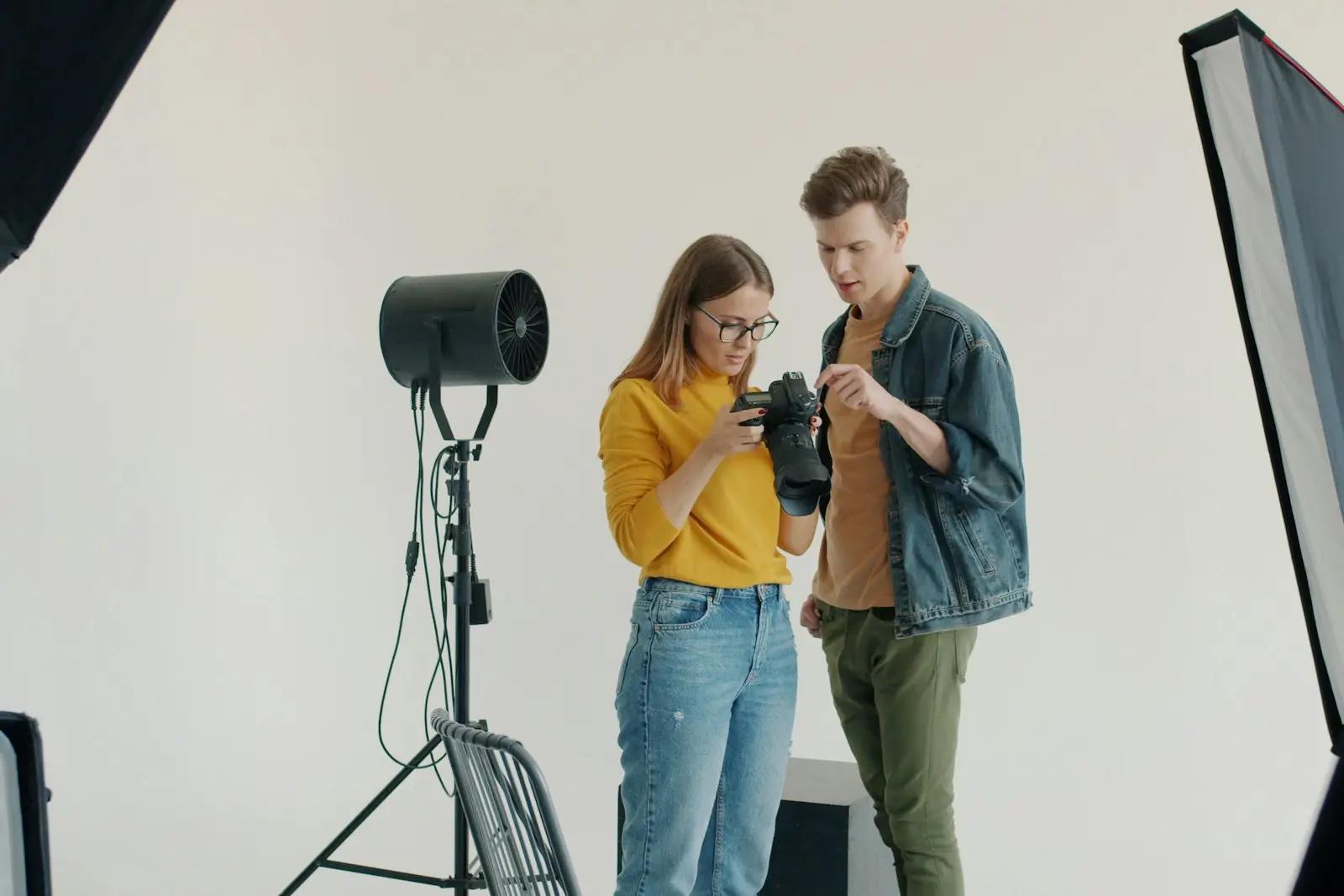To fotografer som ser gjennom bildene på kameraet i et hvitt fotostudio