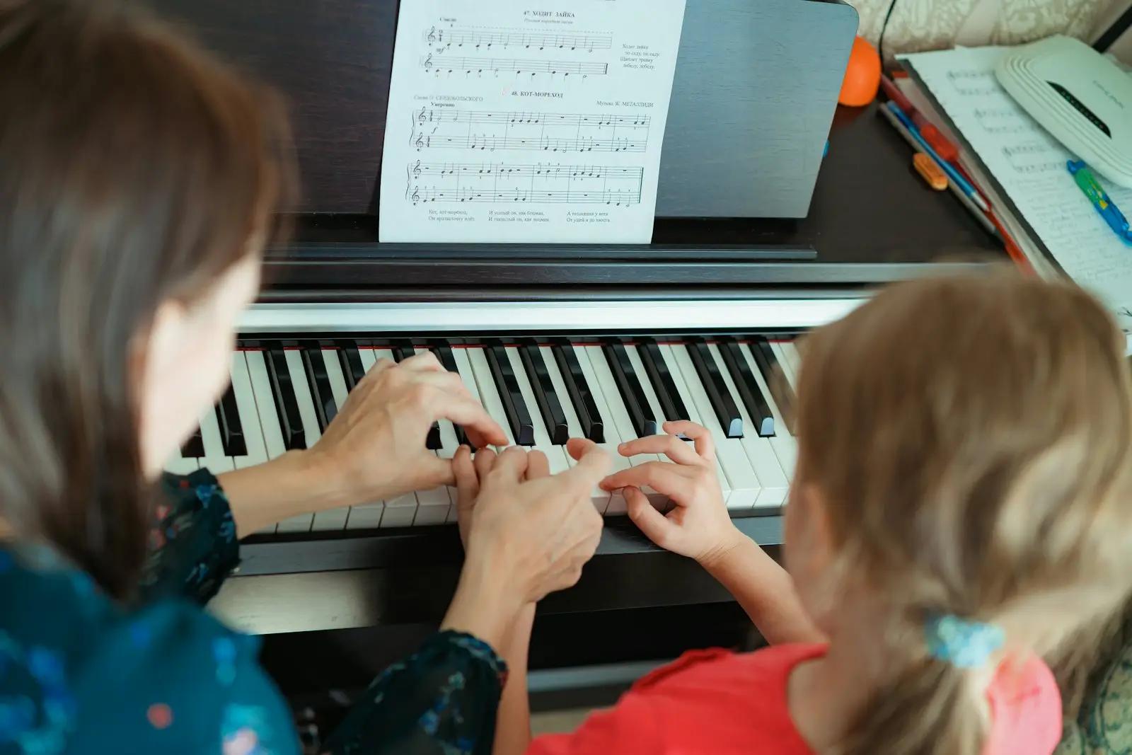 Pianolærer som viser et barn hvordan hun skal spille ved pianoet