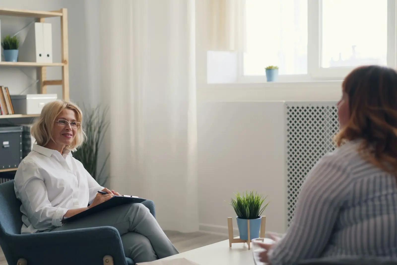 Psykolog med notatblokk i samtale med en klient i et lyst og rolig kontor